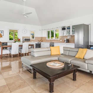 Relax in your bright, open-concept living space where modern comfort meets tropical elegance with sleek furnishings and garden views.