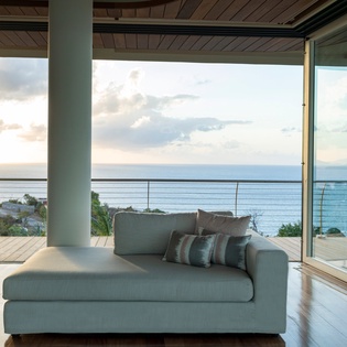 Relax in your stylish living room where floor-to-ceiling windows frame stunning ocean views, creating the perfect seaside retreat.