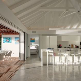 Sleek white kitchen flows seamlessly to your private terrace, where tropical breezes and dining await under swaying palms.