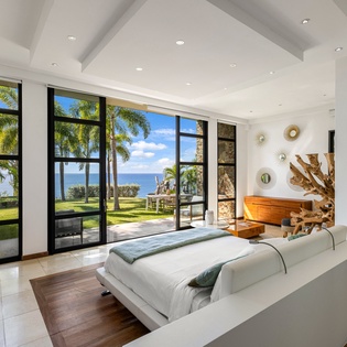 Wake up to stunning ocean views through floor-to-ceiling windows, where tropical breezes and paradise await just steps from your luxurious bed.