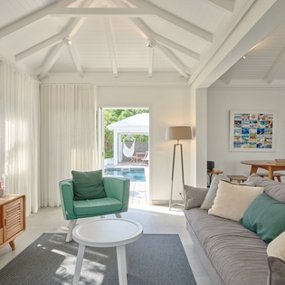 Relax in this bright, airy living space with vaulted ceilings and pool views. Sink into the plush sofa while natural light fills your stylish retreat.