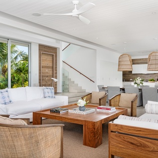 Relax in your elegant living space with woven textures, rich wood accents, and tropical garden views through floor-to-ceiling windows.