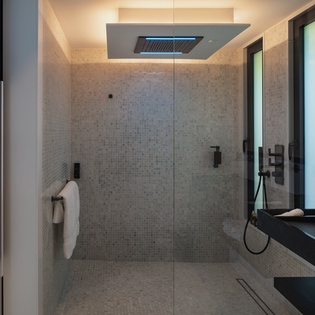 Step into your luxurious spa-like bathroom with rainfall shower, sleek mosaic tiles, and sophisticated black fixtures creating the perfect retreat.