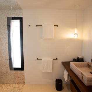 Step into your private spa-like bathroom with warm marble finishes, elegant pendant lighting, and a luxurious walk-in shower.