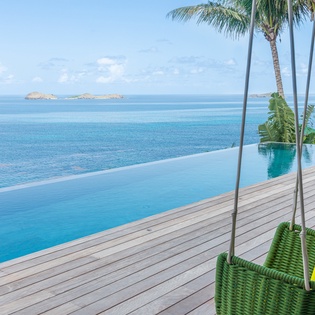 Drift away in colorful hanging swings overlooking your infinity pool and endless ocean views with tropical palms swaying overhead.