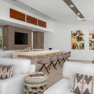 Relax in your stylish open-plan living space featuring modern white furnishings, vibrant artwork, and a sleek kitchen perfect for entertaining.