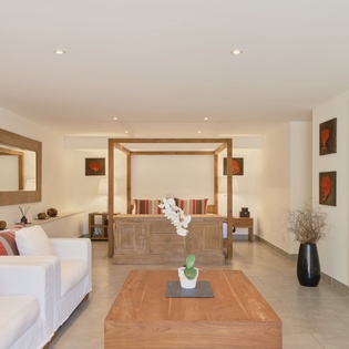 Your spacious suite blends modern comfort with tropical elegance, featuring a four-poster bed and cozy seating area where you can unwind.