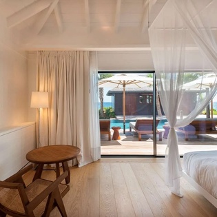 Step into your serene sanctuary where flowing white curtains frame stunning pool and ocean views. Warm wood accents and breezy island elegance invite you to unwind in complete coastal comfort.