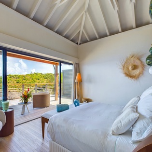 Wake up in your tropical paradise bedroom with stunning views of lush hills through floor-to-ceiling windows.