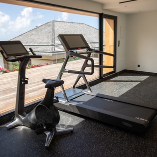 Stay active in your private fitness space with modern equipment and inspiring garden views through floor-to-ceiling windows.