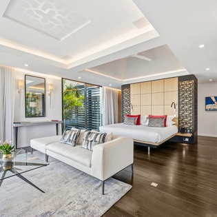 Your elegant suite features rich hardwood floors, soaring coffered ceilings, and tropical garden views through floor-to-ceiling windows.