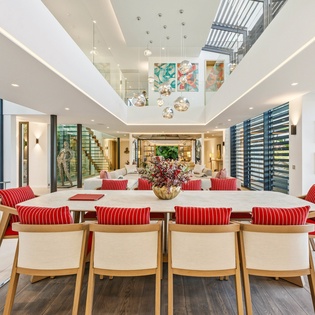 Gather around this stunning dining table where memorable meals and conversations await, bathed in natural light from soaring ceilings above.