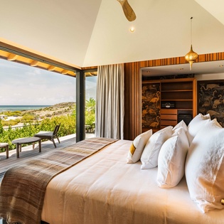 Wake up to sweeping ocean vistas through floor-to-ceiling glass doors that frame the turquoise waters beyond. Sink into plush bedding and let the warm coastal breeze welcome you to paradise.