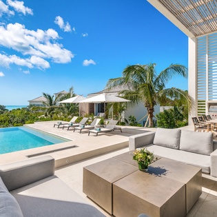Luxurious villa features a stunning infinity pool and modern outdoor lounge with panoramic ocean views and tropical landscaping.