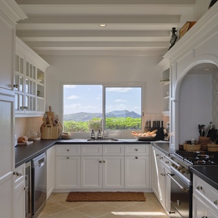 Prepare your favorite meals in this bright kitchen, where sleek countertops, stainless appliances, and stunning mountain views through the window create an inspiring cooking space.