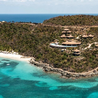 Stunning aerial view of a luxury beachfront resort nestled on a tropical peninsula with pristine turquoise waters and white sand beaches.