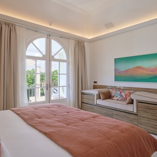 Sink into your serene bedroom sanctuary with warm coral accents, elegant arched windows, and a peaceful mountain artwork that sets the mood for restful nights.