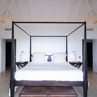 Drift into luxury in your elegant four-poster bed, surrounded by soaring white beams and peaceful serenity.