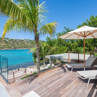 Oceanfront terrace with stunning turquoise views, perfect for relaxing under tropical palms and sunny Caribbean skies.
