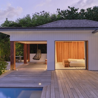 Modern tropical villa featuring a private pool deck and elegantly designed bedroom suite, surrounded by lush natural greenery at twilight.