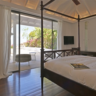 Step into your serene bedroom sanctuary where tropical breezes flow through floor-to-ceiling windows onto your private terrace oasis.