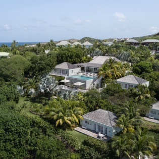 Tropical paradise awaits with this stunning aerial view of the resort nestled among lush palms and tropical vegetation near the Caribbean coastline.