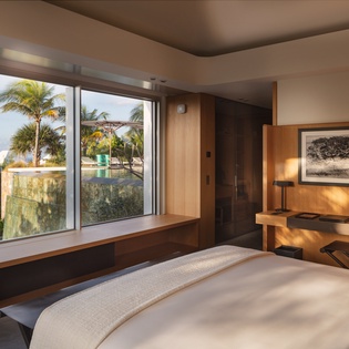 Sink into your plush bed while enjoying tropical views through floor-to-ceiling windows framing swaying palms and lush gardens.