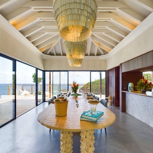 Dine beneath stunning chandeliers with ocean views stretching endlessly beyond your terrace. This dramatic space blends luxury with coastal serenity.