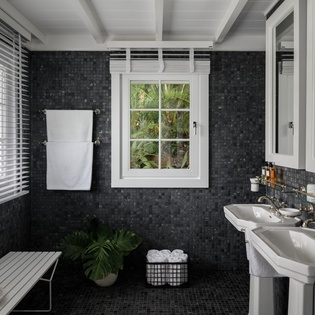 Unwind in your elegant spa-like bathroom with dual sinks, luxurious mosaic tiles, and tropical garden views.