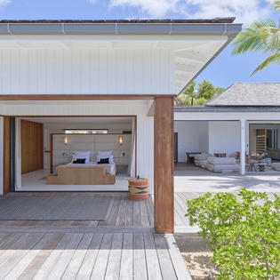 A modern tropical retreat where sleek design meets island serenity, featuring a spacious bedroom that opens seamlessly to your private outdoor living spaces beneath swaying palms.