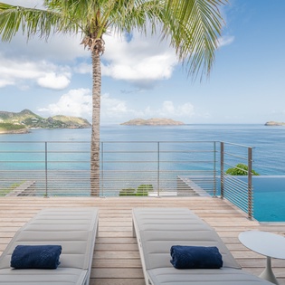 Unwind on your private deck with stunning ocean views, loungers, and tropical palm shade—pure Caribbean paradise awaits.