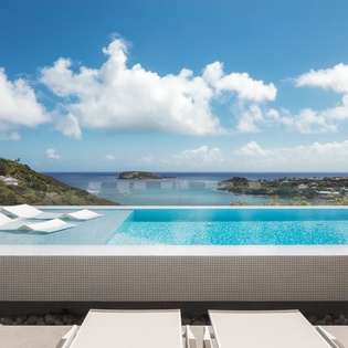 Infinity pool seamlessly blends with turquoise Caribbean waters and dramatic coastline views.
