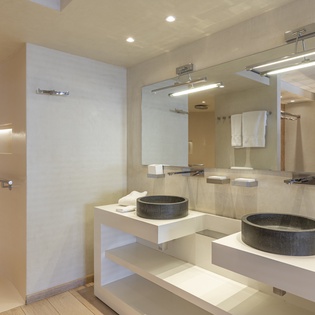 Step into your spa-inspired bathroom featuring striking stone vessel sinks, rainfall shower, and designer lighting—every detail crafted for your comfort and relaxation.
