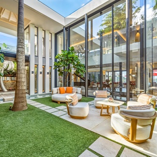 Step into your private courtyard sanctuary where modern luxury meets tropical tranquility, featuring plush seating surrounded by lush palms and open-air elegance.