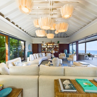 Relax in this stunning open-plan living space with soaring ceilings, elegant chandeliers, and breathtaking ocean views through floor-to-ceiling windows.
