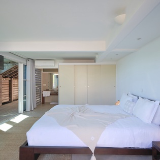 Sink into crisp white linens in your serene bedroom, where natural light flows through floor-to-ceiling windows.