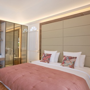 Sink into your luxurious king bed surrounded by warm ambient lighting and elegant wood accents, creating the perfect sanctuary for restful nights.