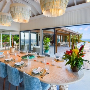 Your elegant dining room features stunning chandeliers and panoramic ocean views through floor-to-ceiling windows, perfect for memorable meals.