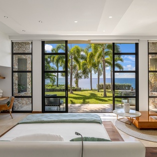 Sink into this stunning oceanfront living space where floor-to-ceiling windows frame palm trees and endless sea views.