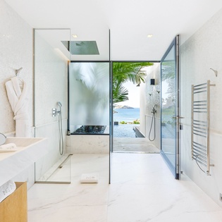 Step into your spa-like sanctuary where marble surfaces gleam and your glass shower opens to tropical views beyond.