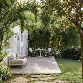 Step onto your private deck surrounded by lush tropical palms and blooming gardens, where comfortable seating awaits your morning coffee moments.