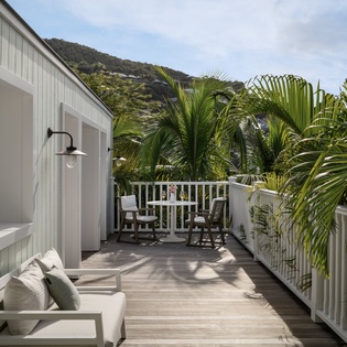 Your private deck with plush seating overlooks tropical palms and scenic mountains, perfect for morning coffee or sunset cocktails.