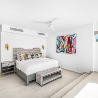 Drift off in this bright, modern bedroom with plush bedding, vibrant art, and natural light streaming through your window.