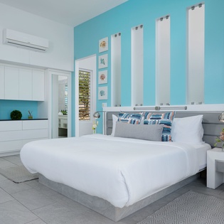 Drift off in this serene coastal-themed bedroom, where crisp linens meet playful turquoise accents and beach-inspired art awaits your arrival.