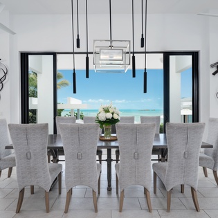 A stunning dining space that opens seamlessly to turquoise waters and endless sky. Gather with loved ones around this elegant table while ocean breezes drift through and natural light fills the room.