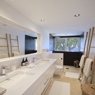 Unwind in your spa-like bathroom with dual sinks, a soaking tub, and serene garden views through the window.
