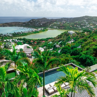 Stunning aerial view showcasing the property's hillside location with tropical coastline, lagoon, and lush mountains.