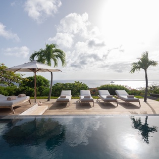 An inviting tropical paradise awaits beyond this pristine infinity pool, where ocean breezes and swaying palms frame breathtaking coastal panoramas perfect for your island escape.