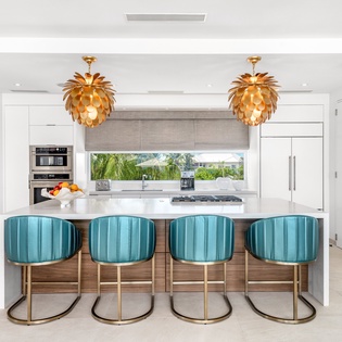 Gather around your stunning kitchen island with turquoise velvet stools beneath statement pineapple pendant lights, perfect for cooking and entertaining.