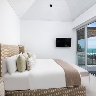Wake up to stunning ocean views from your bed, where crisp linens and modern comfort meet paradise through floor-to-ceiling windows.